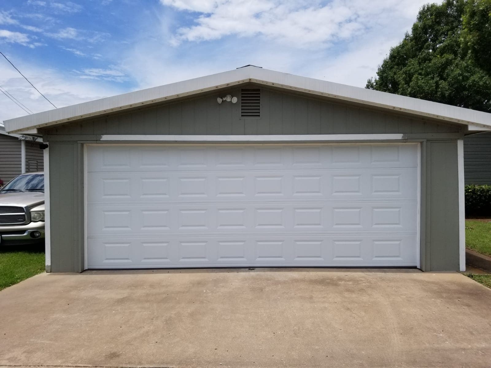 Straight-on view of a white two-car garage door on a green detached garage